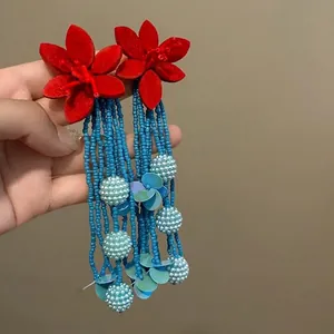 Detailansicht langer Boho-Ohrringe mit roten Stoffblumen und blauen Perlenketten