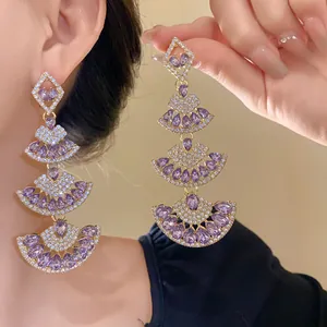 Detail view of luxurious purple fan-shaped dangle earrings with rhinestone inlay