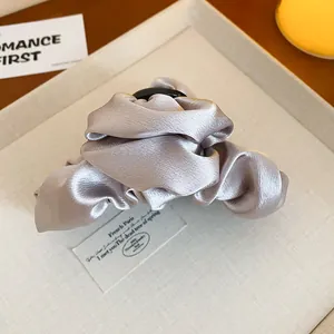 Dettaglio di una molletta per capelli francese in raso con elegante trama scrunchie.