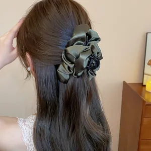 Dettaglio ravvicinato di una clip per capelli in raso verde oliva in stile francese