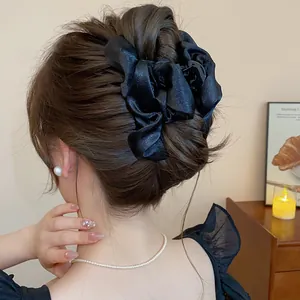 Primo piano di una clip per capelli in raso nero stile francese su un'acconciatura elegante.
