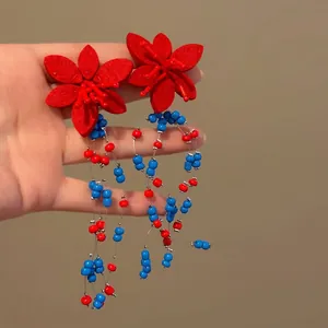 Detaillierte Ansicht von roten Stoffblumen-Ohrringen mit lebhaften blau-roten Perlenquasten