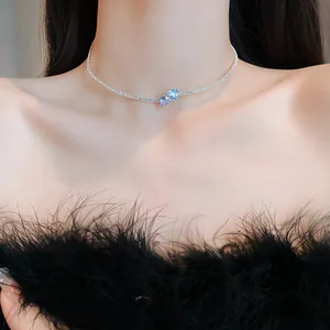 Close-up view of a minimalist zircon heart choker necklace worn by a model with a black top.