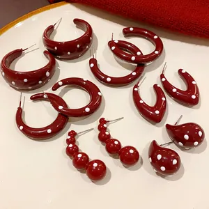 Detailed view of various retro burgundy polka dot earrings on a white ceramic plate