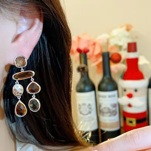 Close-up of elegant amber glass teardrop dangle earrings worn during a festive holiday event