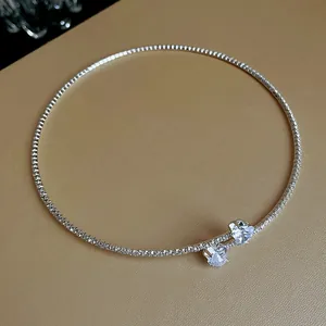 Macro view of silver-tone choker necklace featuring dual heart-shaped zircon pendants.
