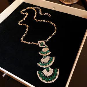 Detailed view of luxury tiered fan-shaped necklace featuring green and white gemstones