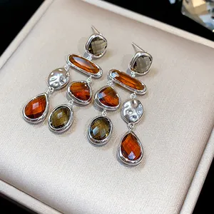 Close-up detail of geometric drop earrings featuring amber glass and hammered silver.