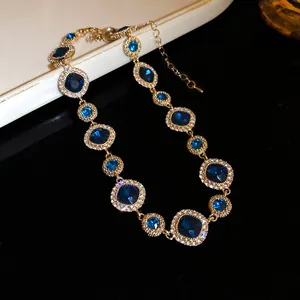 Dettaglio di una lussuosa collana placcata in oro con gemme blu e aloni di strass.