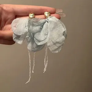 Primo piano di orecchini a fiore in tessuto blu con cuori dorati e nappe di perle