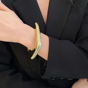 Bracelet jonc ouvert doré brillant géométrique irrégulier avec un design minimaliste.