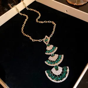 Elegant gold tiered fan necklace with green gemstones and sparkling micro-crystals