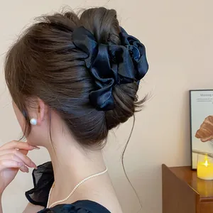 Vista dettagliata di un'elegante pinza per capelli in raso nero in uno chignon chic