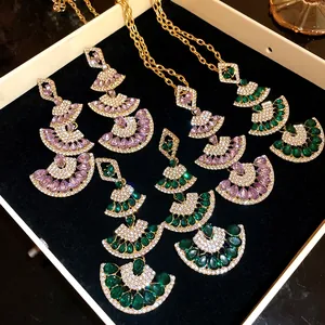 Detail view of fan-shaped jewelry set with sparkling green and purple gemstones.