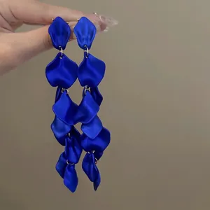 Dettaglio macro di orecchini pendenti con petali di fiori in tessuto blu reale e aghi