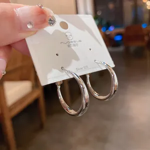 Pendientes de aro minimalistas en plata 925 pulida para mujer, detalle de joyería fina.