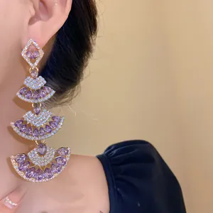 Close-up of three-tier fan-shaped dangling earrings with purple crystals