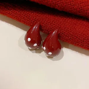 Close-up detail of vintage red water drop earrings with white polka dots on knit fabric