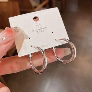 Vista macro detallada de pendientes de aro minimalistas con aguja de plata 925 chic