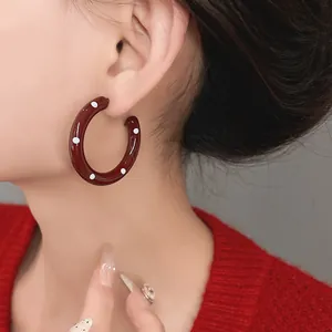 Macro detail shot of vintage burgundy enamel hoop earring with white polka dots on model