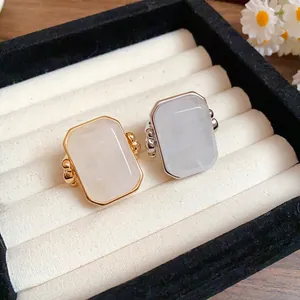 Primo piano di eleganti anelli in oro e argento con grande pietra naturale quadrata in scatola.
