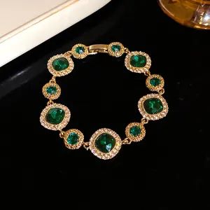 Elegante bracciale dorato con pietre verde smeraldo e dettagli in strass
