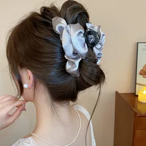 Primo piano di un'elegante molletta per capelli in raso grigio portata su uno chignon.