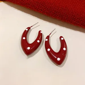 Close-up view of retro dark red polka dot U-shaped geometric earrings with steel needles