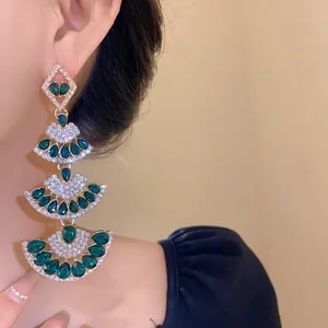 Detailed view of glamorous tiered fan-shaped earrings with emerald green crystals