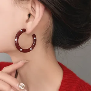 Close-up of retro dark red hoop earrings with white polka dots worn by an Asian model