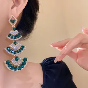 Close-up of elegant tiered fan-shaped emerald green crystal dangle earrings worn by a model