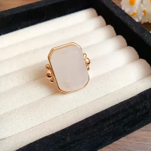 Vista dettagliata di un anello in pietra naturale quadrata con montatura vintage oro.