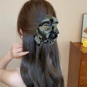 Elegante molletta per capelli in raso verde scuro mostrata su un'acconciatura da dietro.