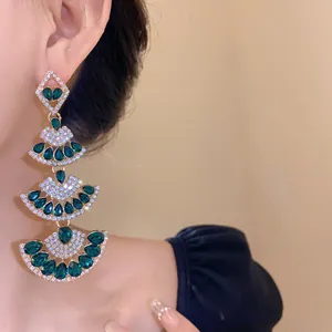 Close-up of elegant emerald green fan-shaped drop earrings with sparkling crystals