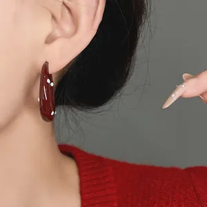 Close-up detail of elegant dark red oil drip earrings with white polka dot patterns