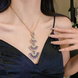 Close-up of luxury tiered fan-shaped pendant necklace with purple crystals on model.