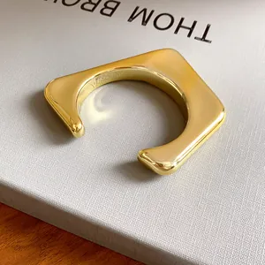 Gros plan d'un bracelet jonc ouvert géométrique irrégulier fini en or.