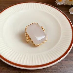 Dettaglio di un anello minimalista dorato con una grande pietra naturale rettangolare