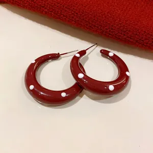 Detail view of retro red polka dot hoop earrings featuring high-gloss drip oil finish