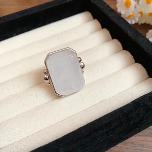 Primo piano di un anello in pietra naturale quadrata d'argento su un vassoio di velluto crema.