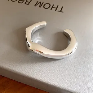 Gros plan d'un bracelet jonc ouvert argenté avec un design géométrique irrégulier épuré