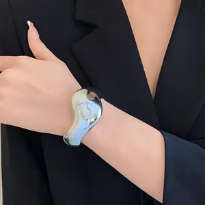 Gros plan détaillé d'un bracelet manchette ouvert géométrique irrégulier argenté au poignet