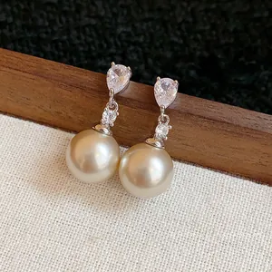 Elegant silver needle drop earrings with pear-shaped zirconia and champagne pearls.
