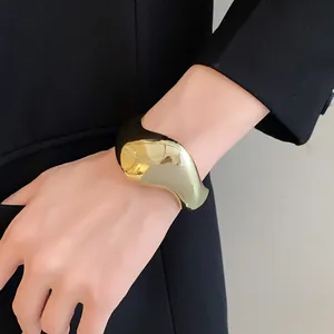 Gros plan d'un bracelet manchette géométrique doré brillant sur un poignet