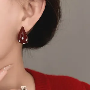 Close-up detail of vintage dark red waterdrop stud earrings with white polka dots