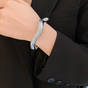 Gros plan d'un bracelet ouvert en argent géométrique irrégulier porté sur un poignet