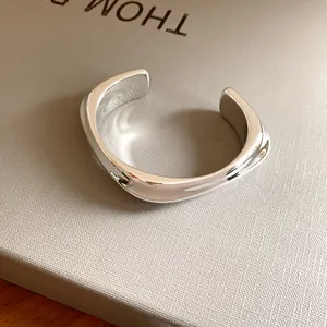 Gros plan d'un bracelet jonc ouvert géométrique irrégulier argenté minimaliste au fini poli lisse