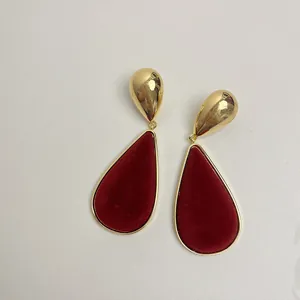 Close-up of vintage red velvet teardrop earrings with gold finish, showing fine texture.