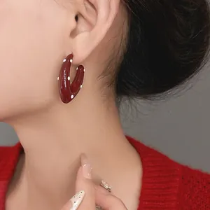 Close-up of retro red enamel drop earrings with white polka dot patterns on a model.