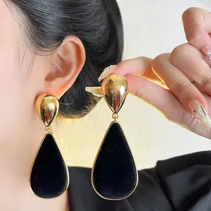 Detailed macro view of retro black velvet teardrop earrings with a gold metallic finish